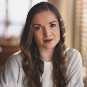 woman in white sweater crossing hands while smiling